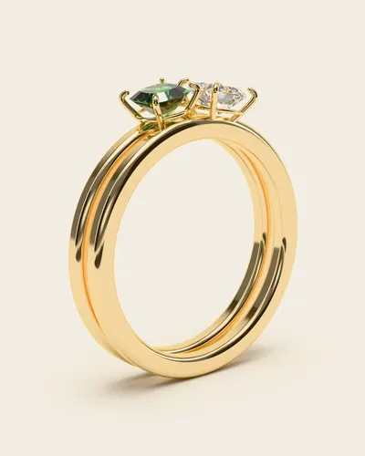 Mazi Two-Stone Ring: a split band holding two square stones side by side, one clear and one green, in gold-plated 925 silver, on an ivory background.