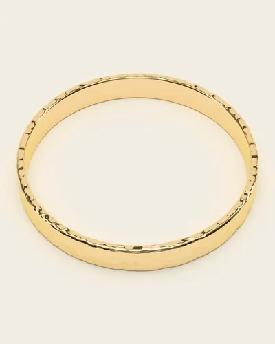 Petra Hammered Bangle: a narrow bangle hammered all over, in gold-plated 925 silver, on an ivory background.